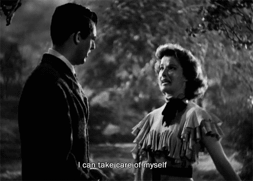 A black and white gif from an old movie of a woman saying "I can take care of myself" just before stumbling over a tree branch and falling